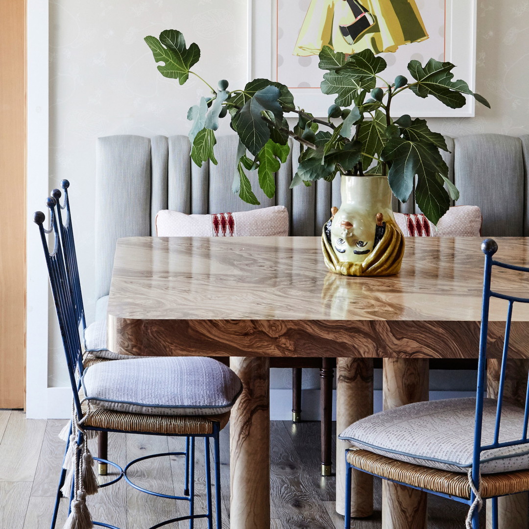 a dining room table with chairs and a vase with a plant in it