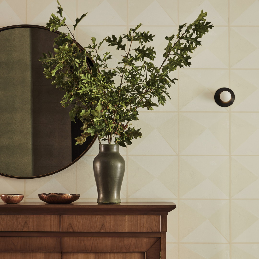 a vase with a plant on a table next to a mirror