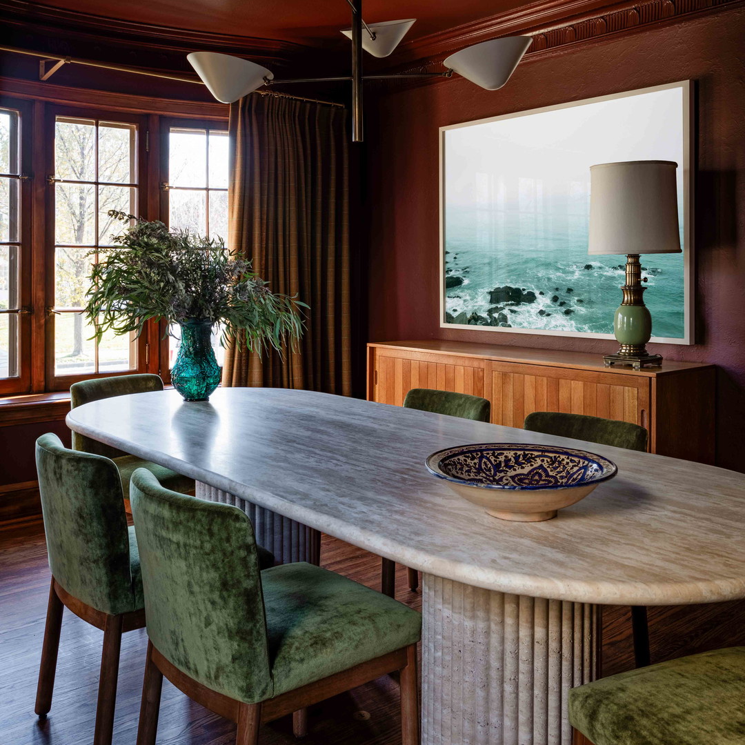 a dining room table with green chairs and a painting on the wall