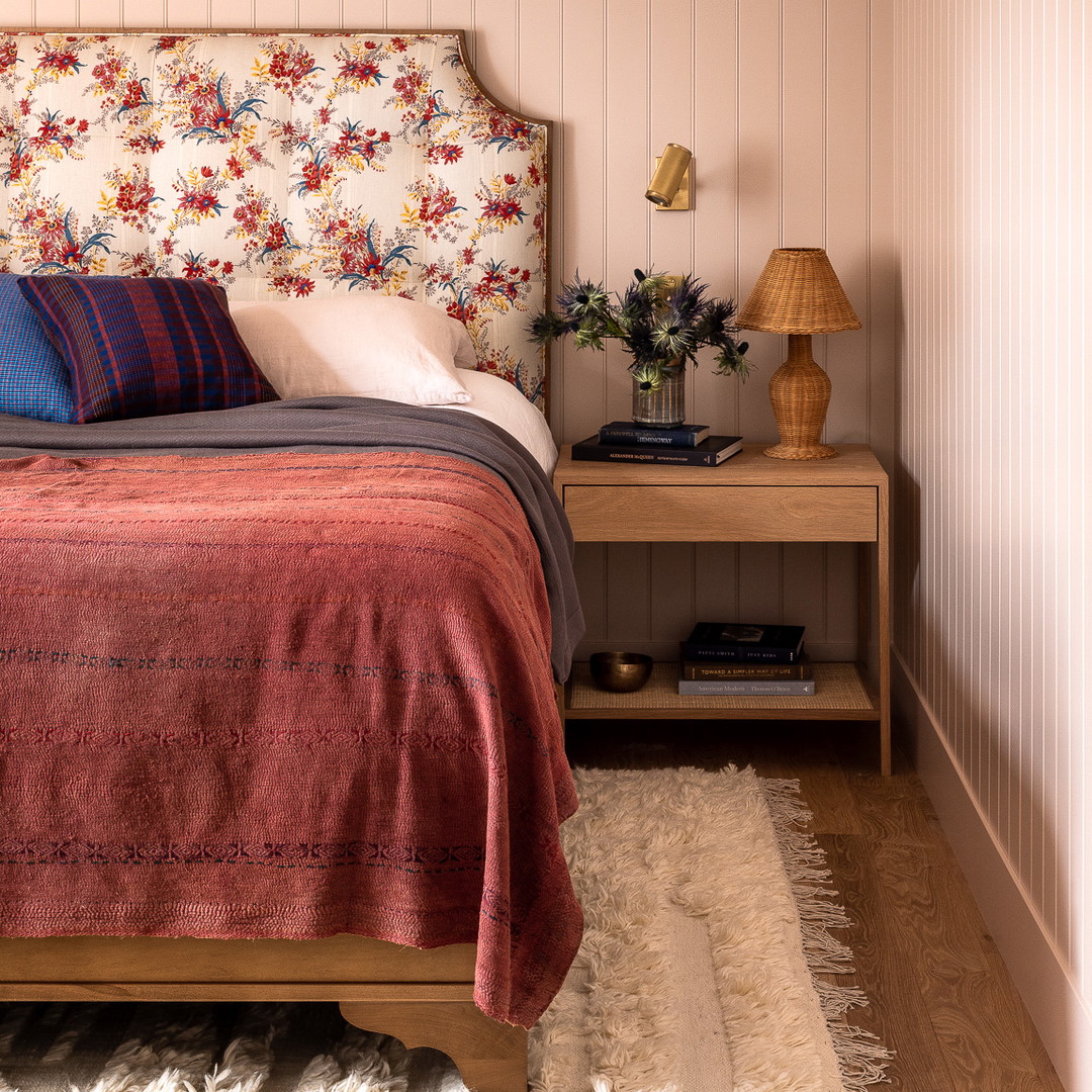 a bed with a floral headboard and a wooden night stand