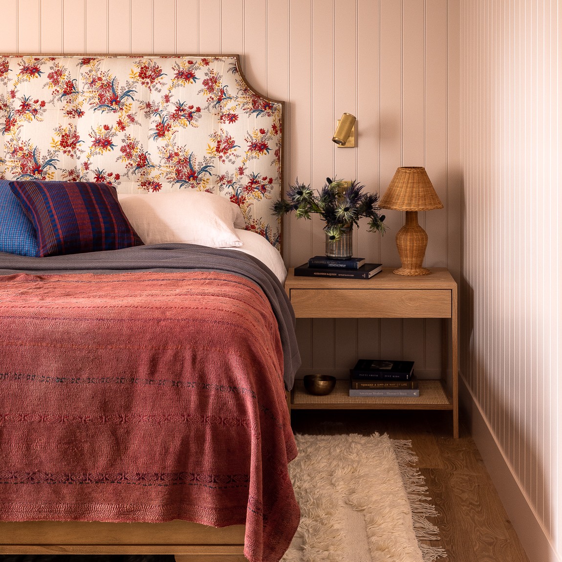 a bed with a floral headboard and a wooden night stand