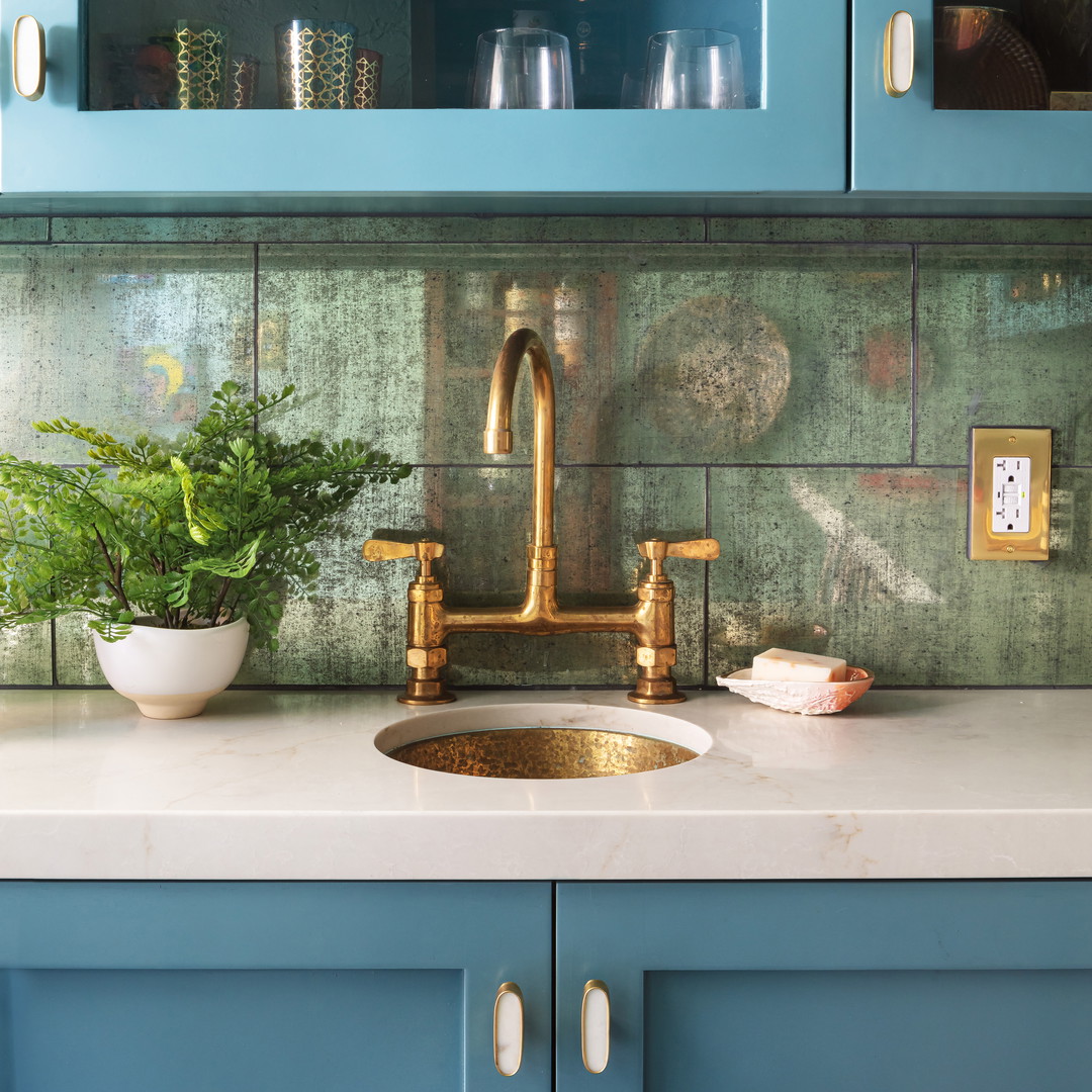 a sink with a gold faucet and a potted plant