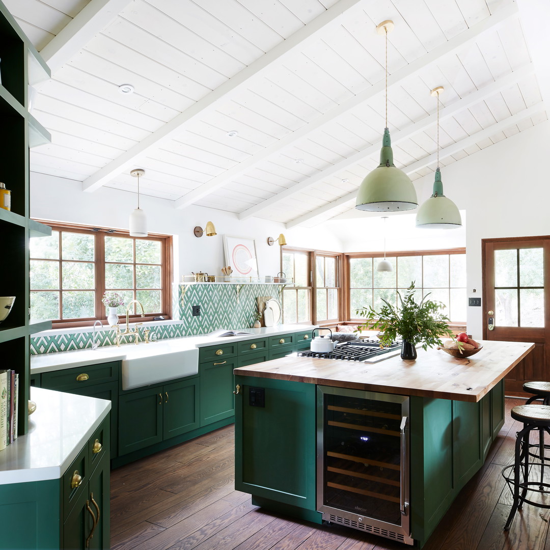 a kitchen with green cabinets and wooden floors