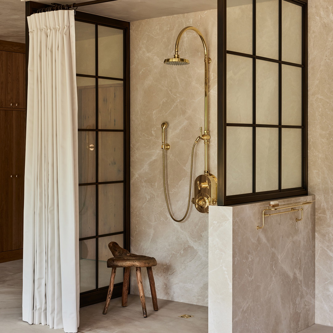 a bathroom with a walk in shower next to a wooden stool