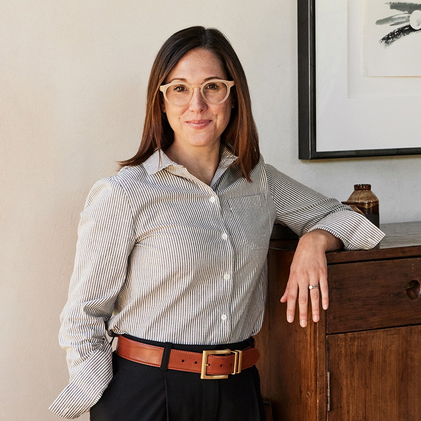 a woman standing next to a wooden cabinet