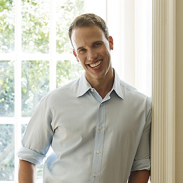 a man in a blue shirt and khaki pants standing in a doorway