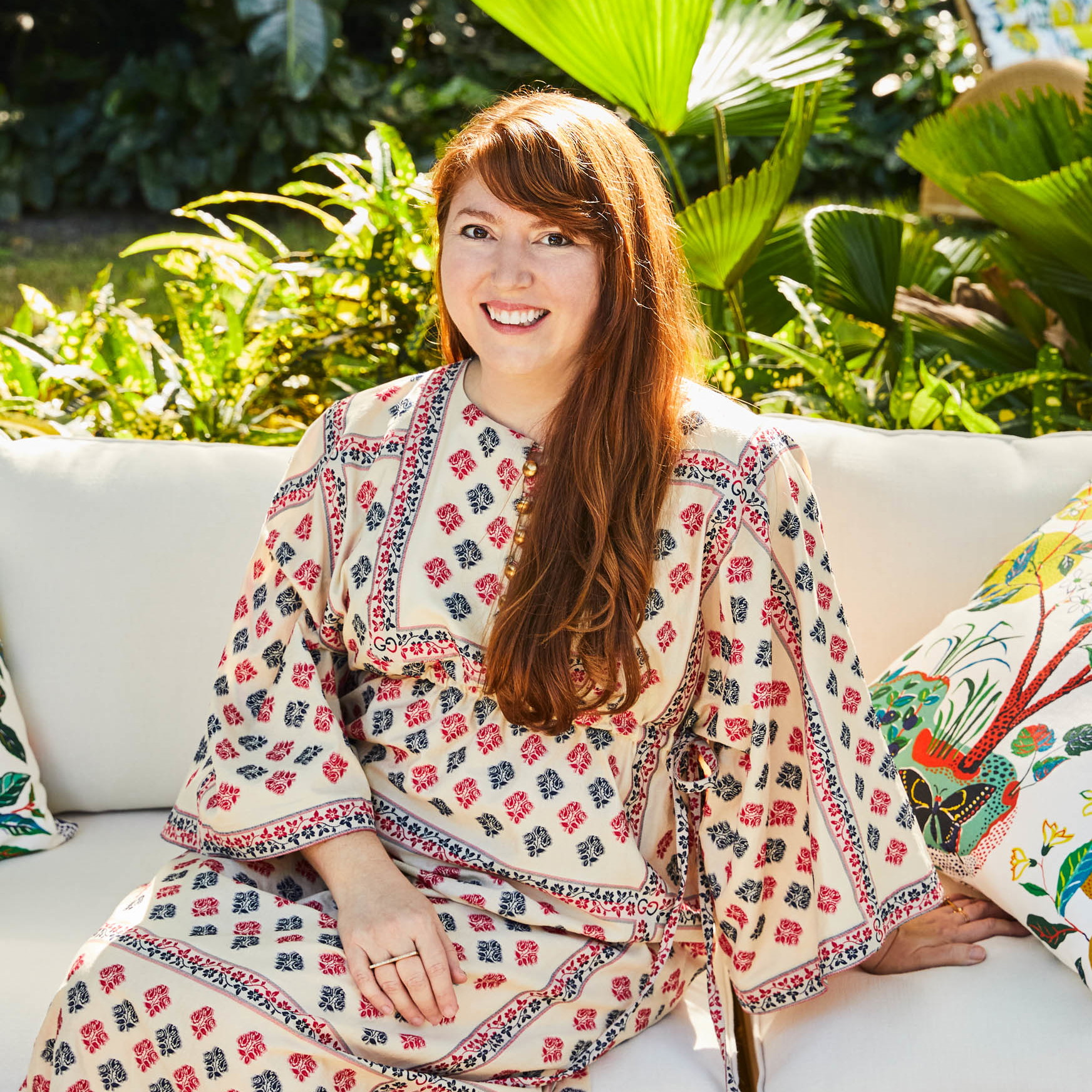 a woman sitting on a white couch in a garden