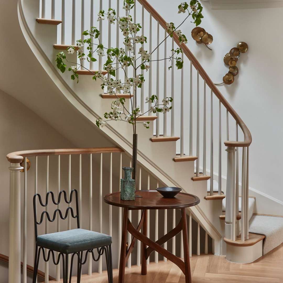 a table with a vase of flowers next to a stair case