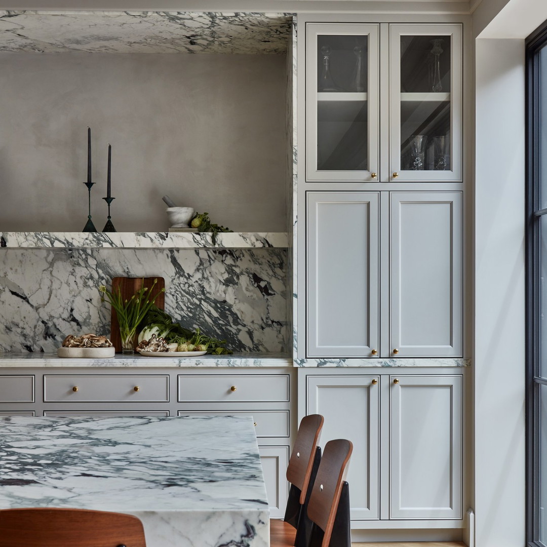 a kitchen with a marble counter top and wooden chairs