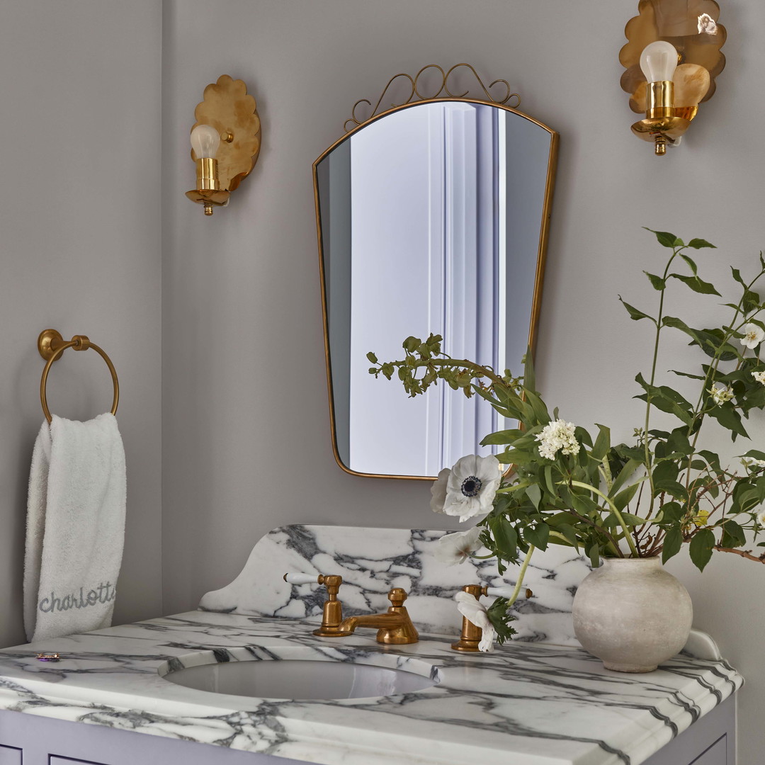 a bathroom with a marble counter top and gold accents