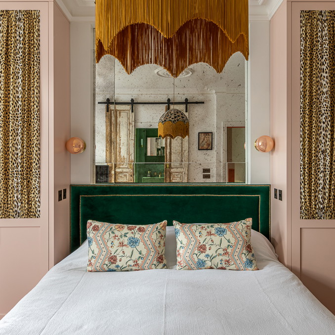 a bedroom with pink walls and a green headboard