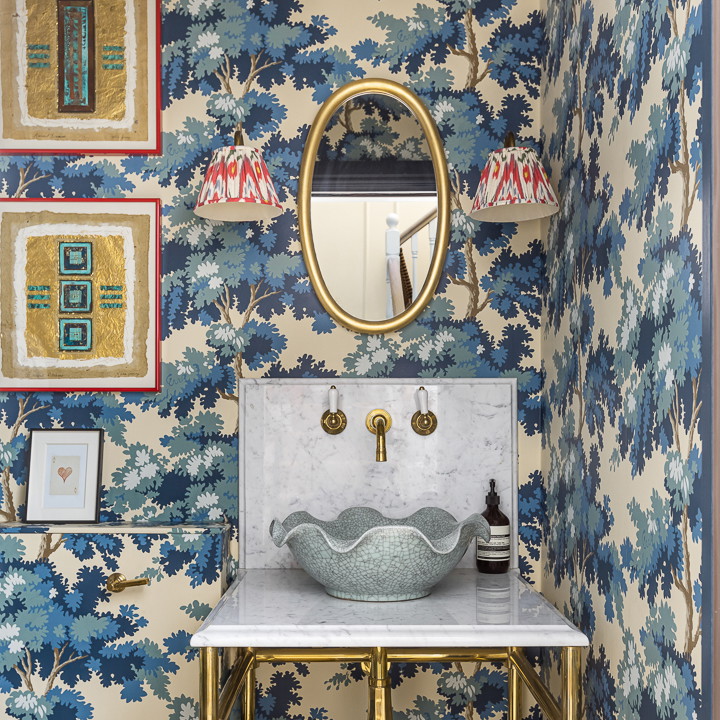 a bathroom with blue and white wallpaper and gold fixtures