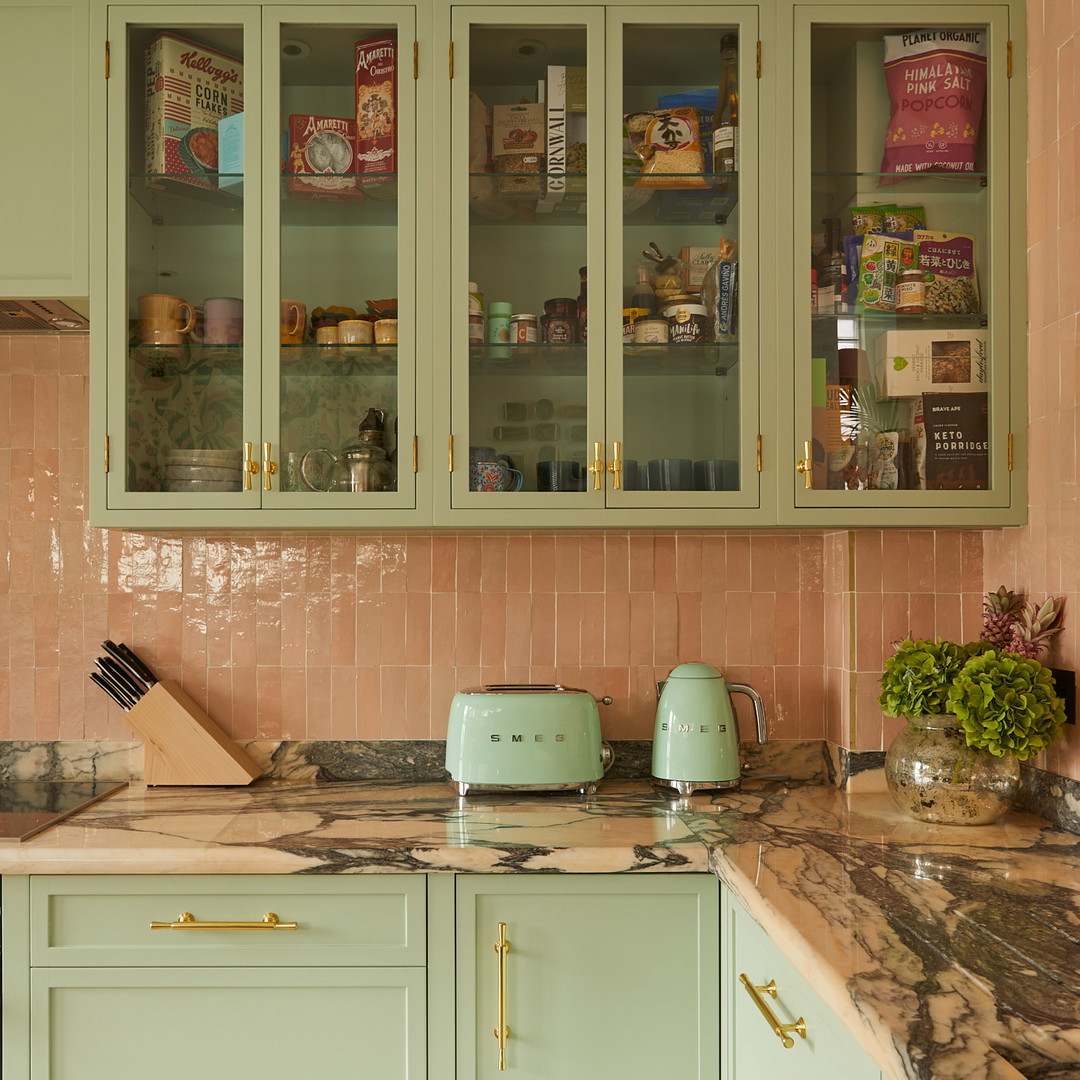 a kitchen with green cabinets and marble counter tops