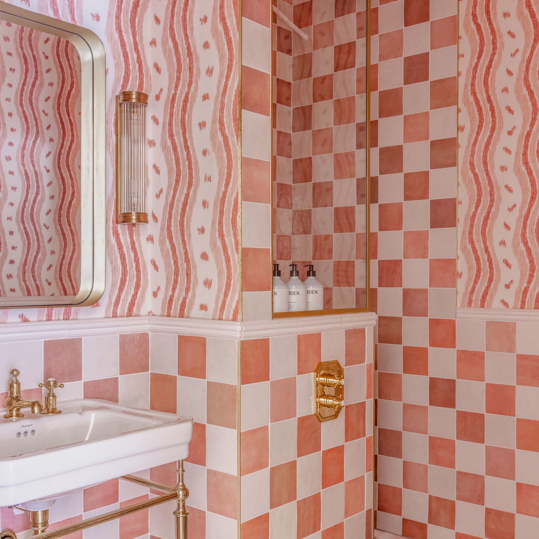 a bathroom with pink and white tiles and gold fixtures