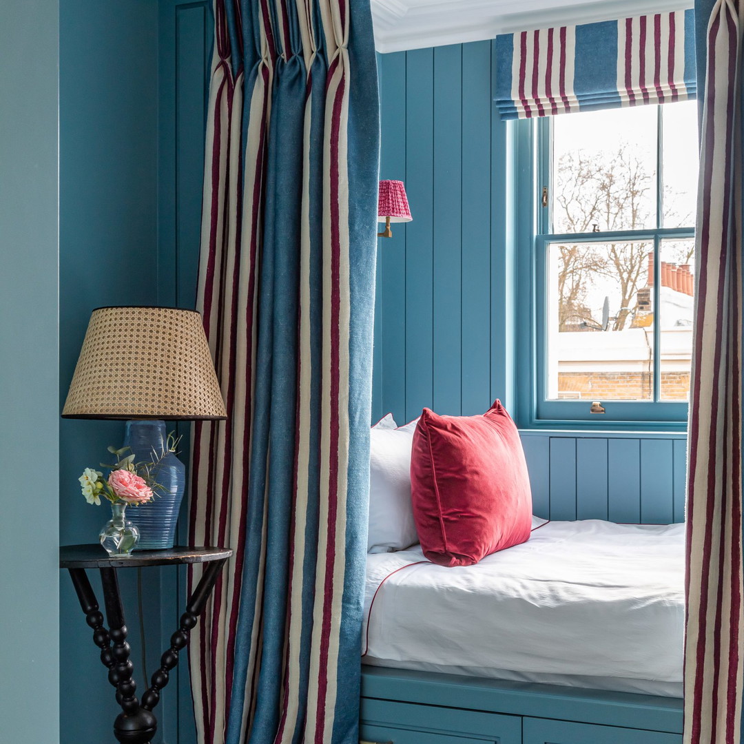 a bedroom with blue walls and red and white curtains