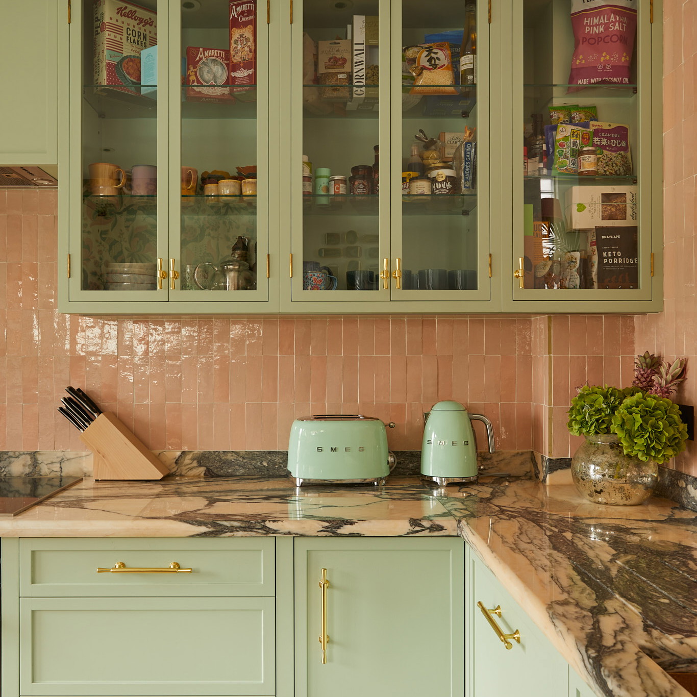 a kitchen with green cabinets and marble counter tops