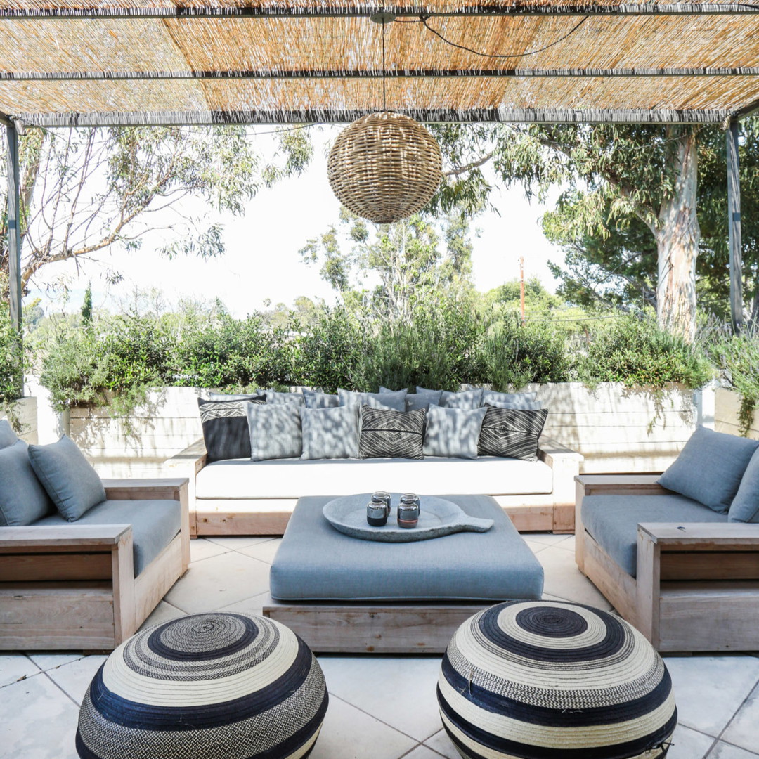 a covered patio with a couch, ottoman and coffee table