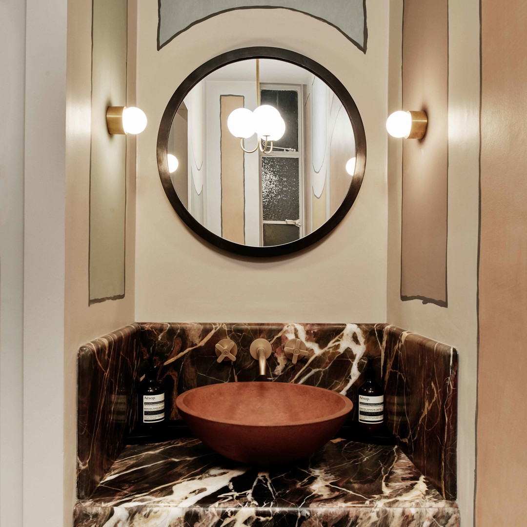 a bathroom sink with a round mirror above it