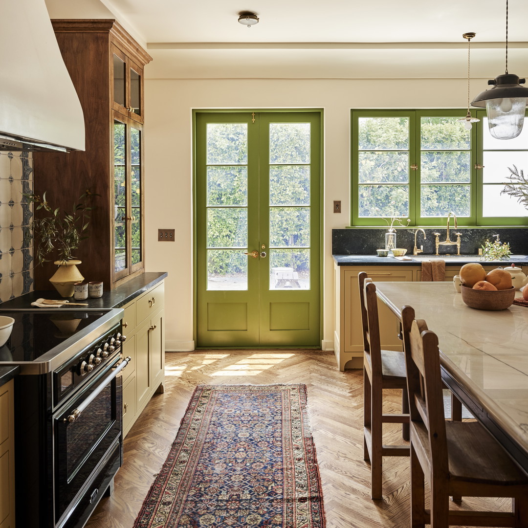 a kitchen with a green door and a rug on the floor