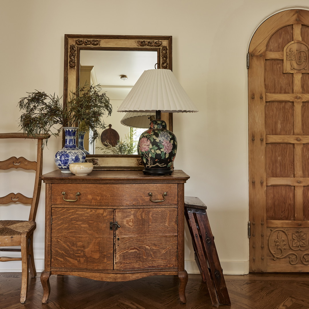 a wooden dresser with a lamp on top of it