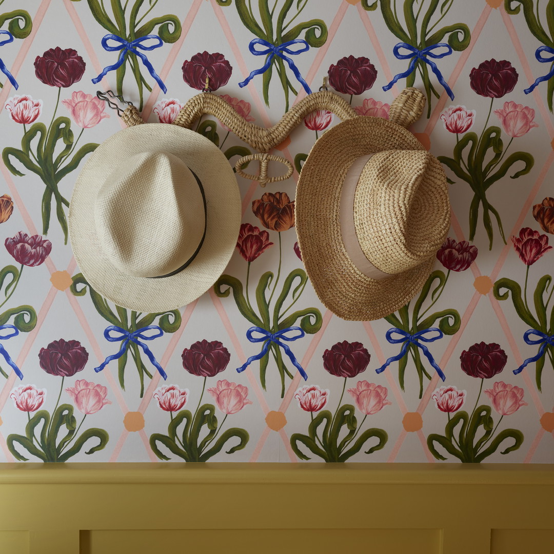 two hats hanging on a wall next to a wallpaper