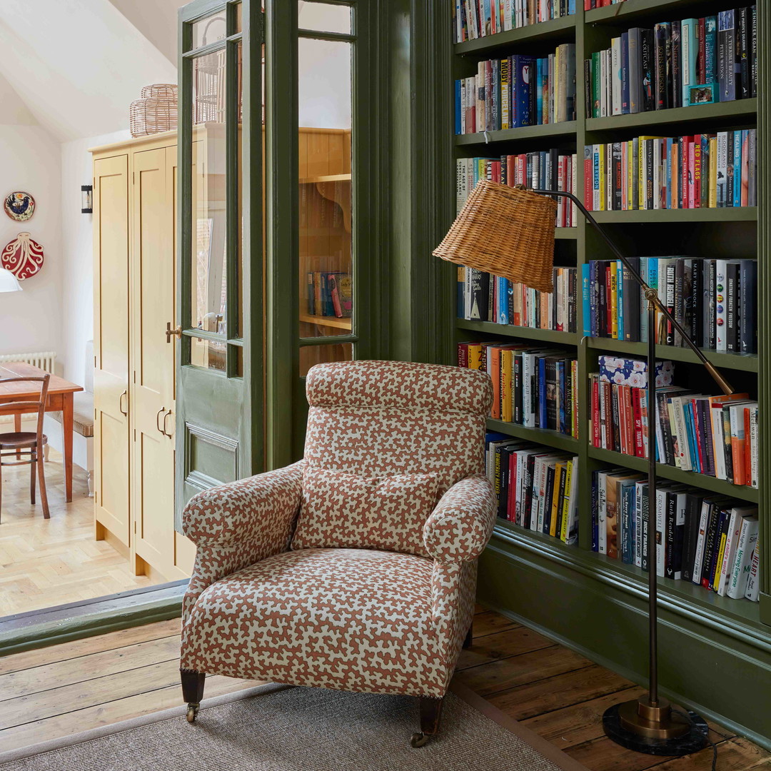 a living room with a chair and a book shelf