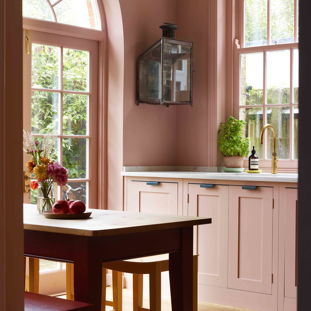 a kitchen with pink walls and wooden floors