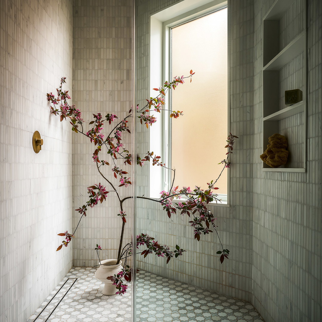 a bathroom with a vase of flowers on the window sill