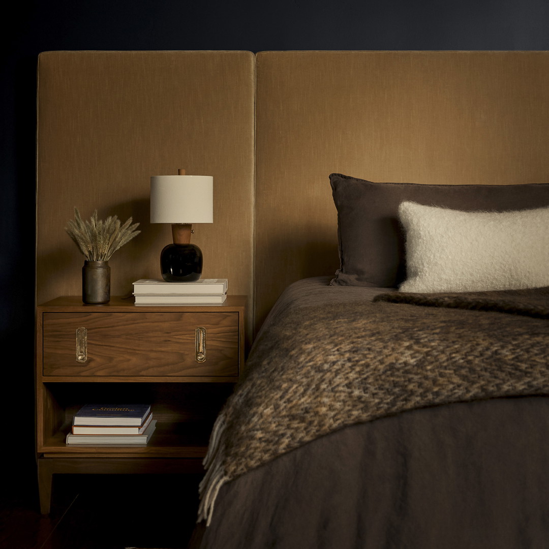 a bedroom with a bed, nightstand, and lamp