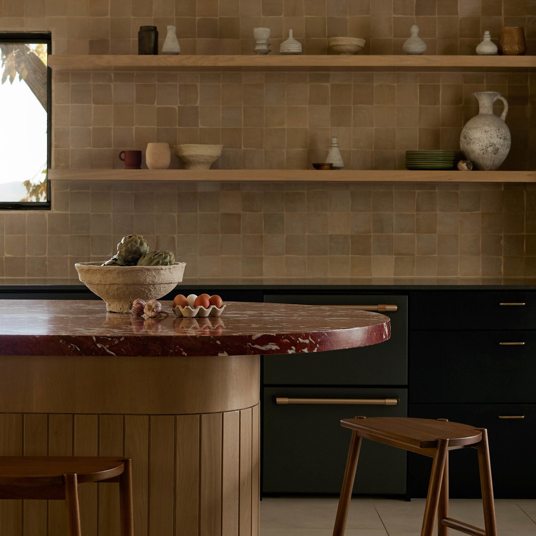 a kitchen with a counter, stools and shelves