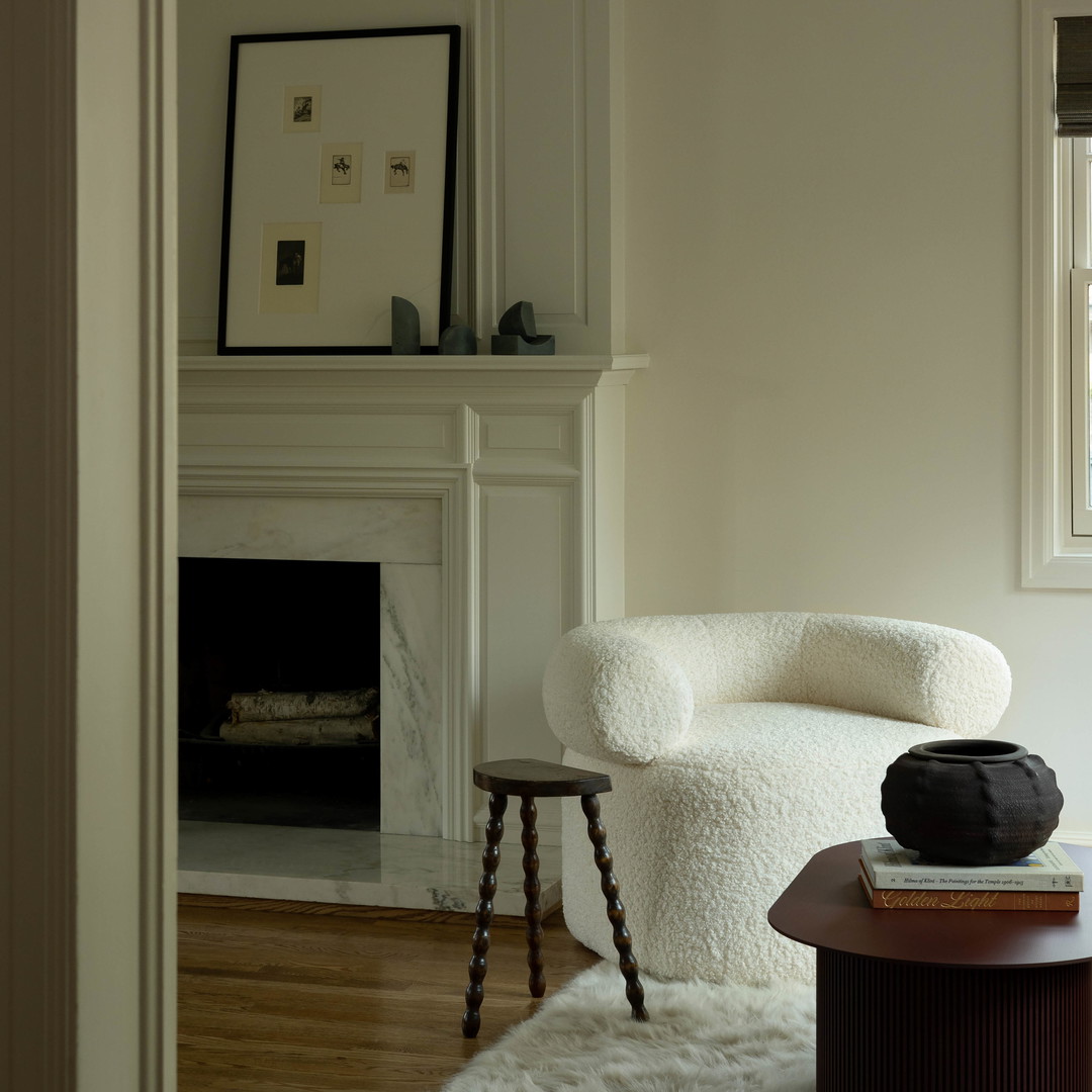 a living room with a white chair and a fireplace