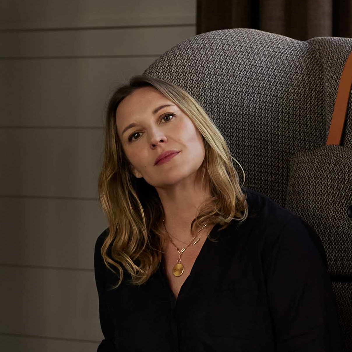 a woman sitting in a chair in front of a fireplace