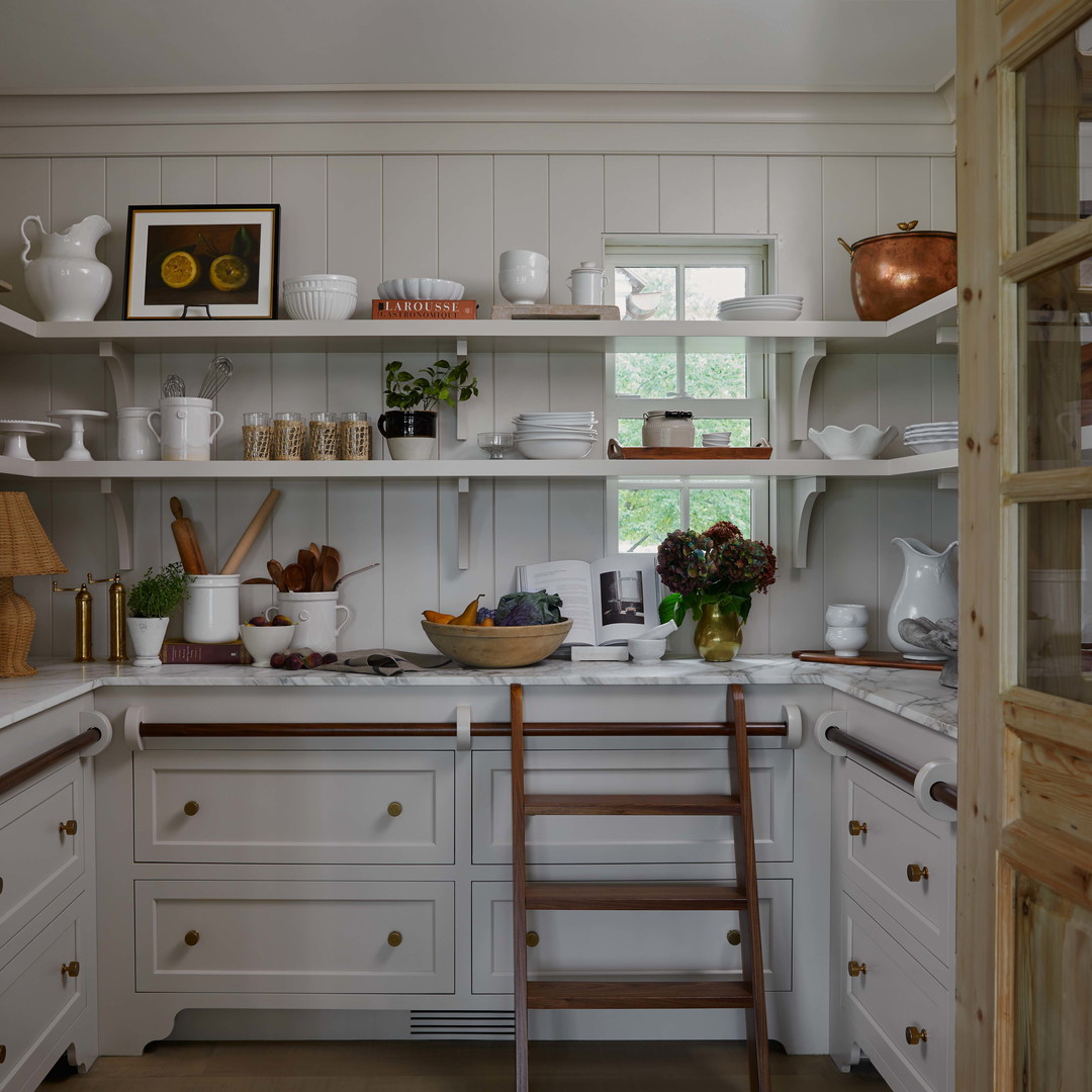 a kitchen with white cabinets and shelves filled with dishes