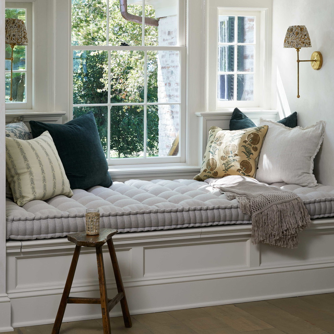 a window seat with pillows on it in front of a window