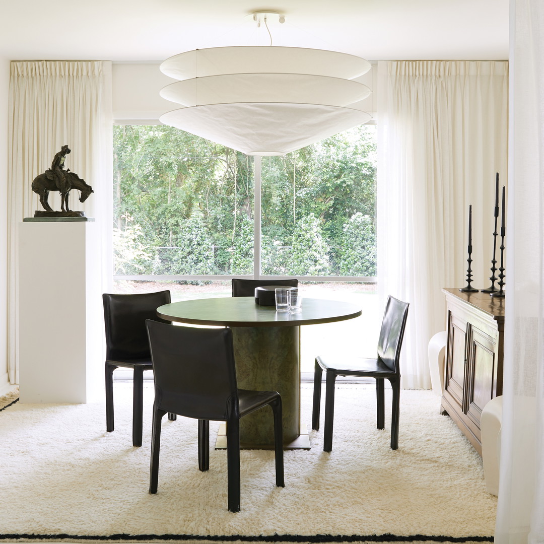 a dining room with a round table surrounded by black chairs