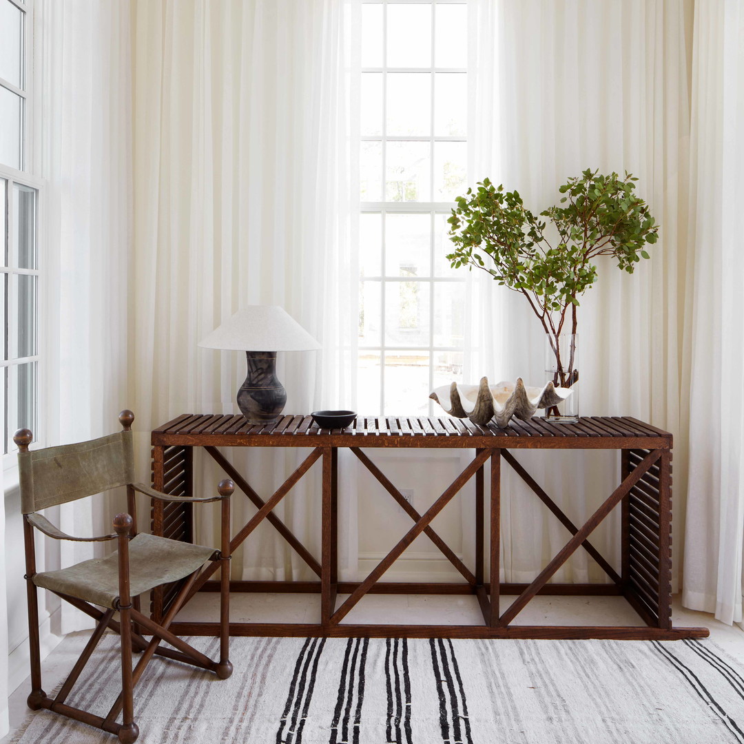 a room with a table, chair, lamp and a window