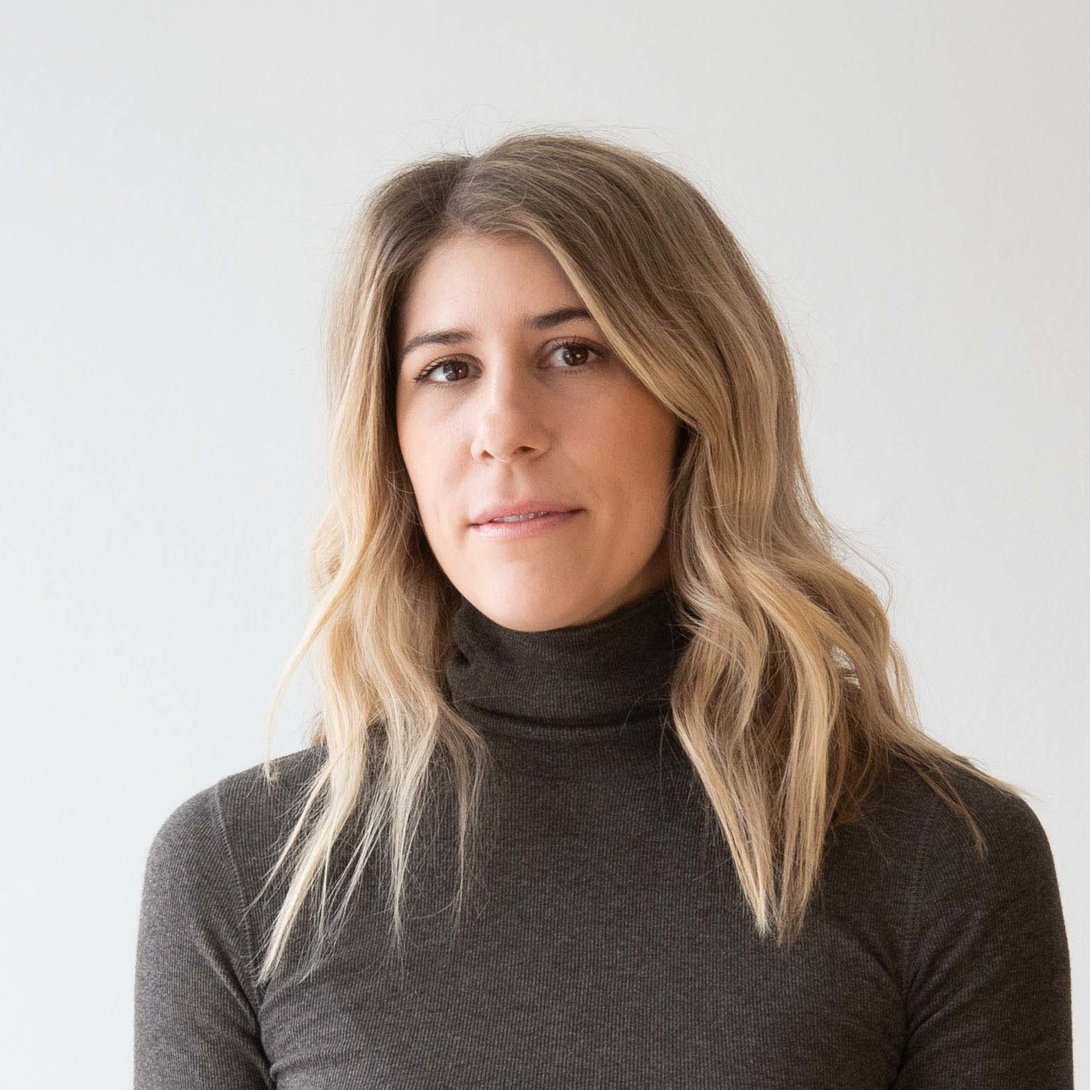 a woman standing in front of a white wall