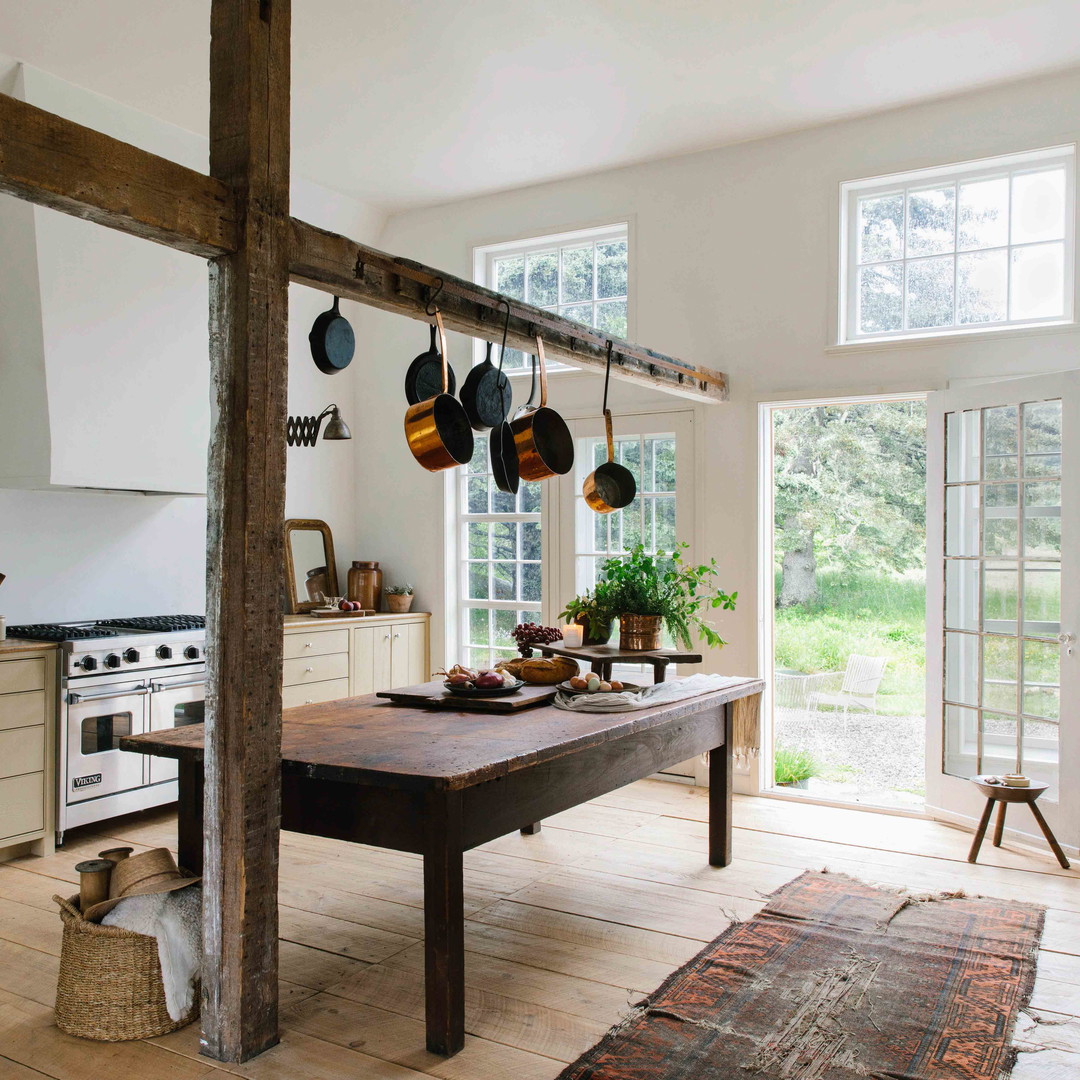 a kitchen with a table, stove, oven, and windows