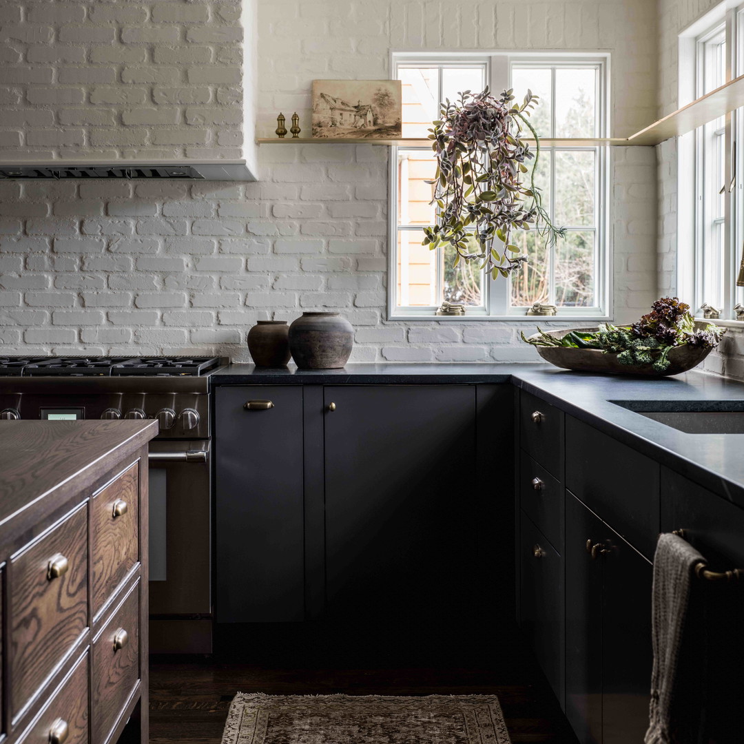 a kitchen with black cabinets and a white brick wall