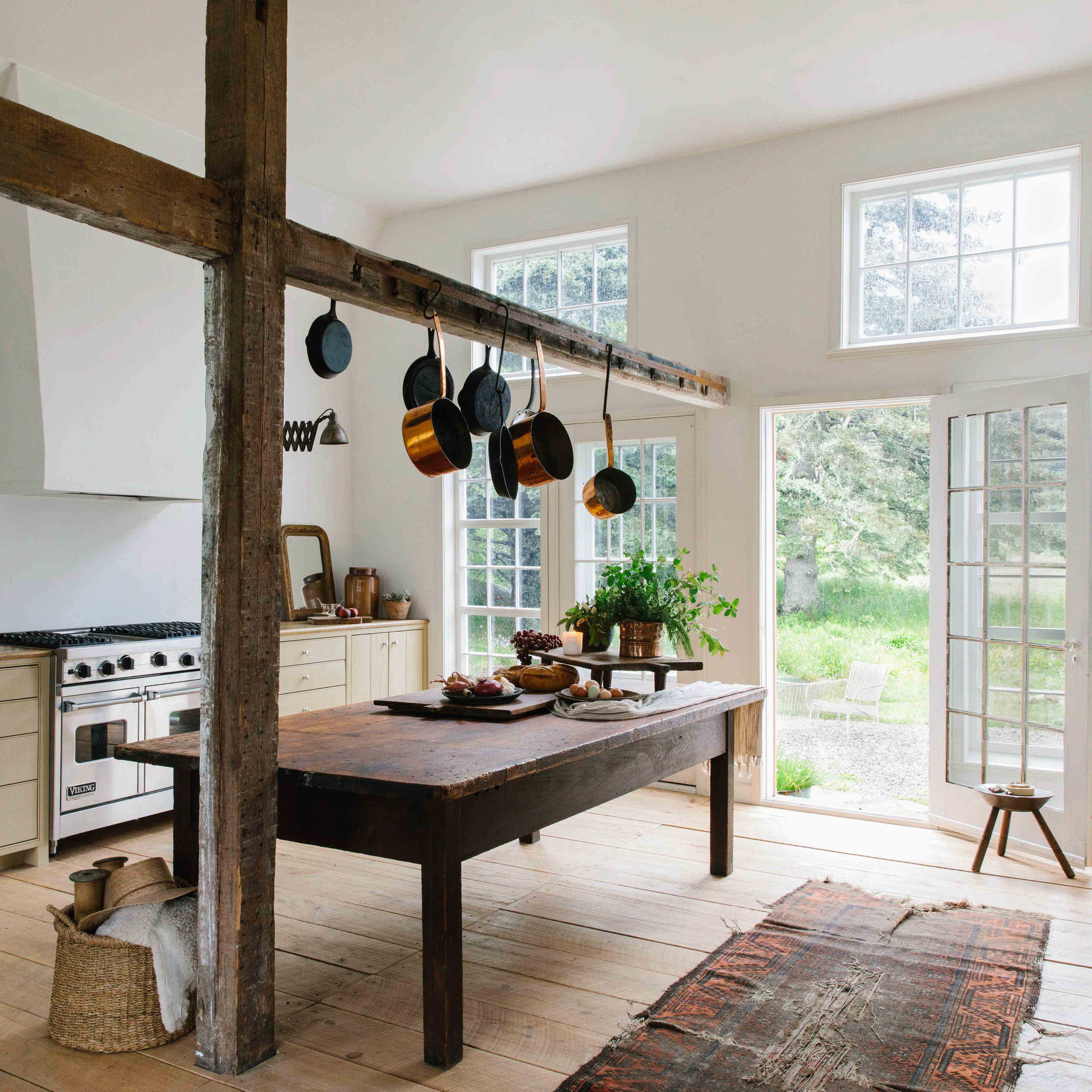 a kitchen with a table, stove, oven, and windows