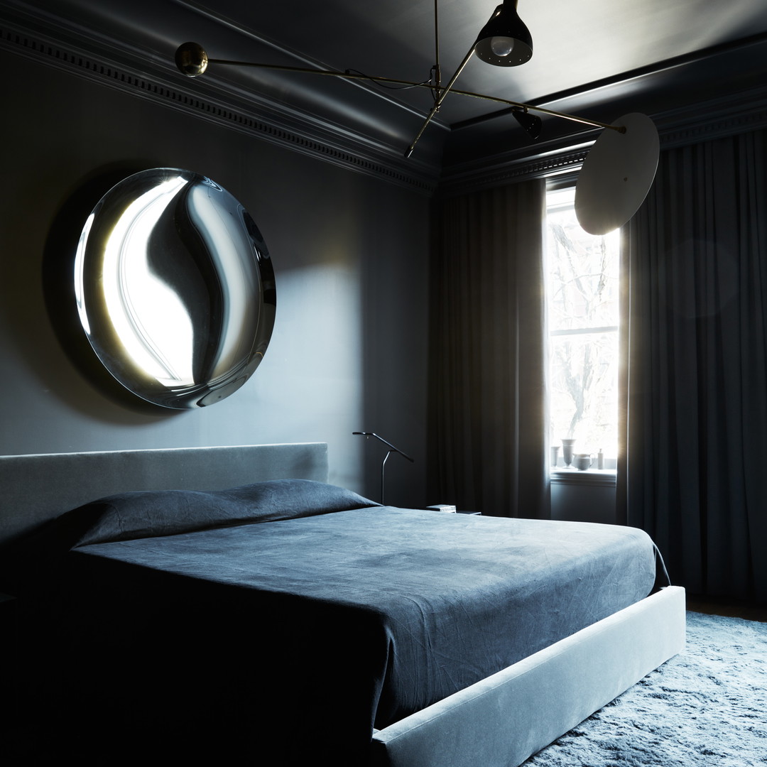 a bedroom with a bed and a round mirror