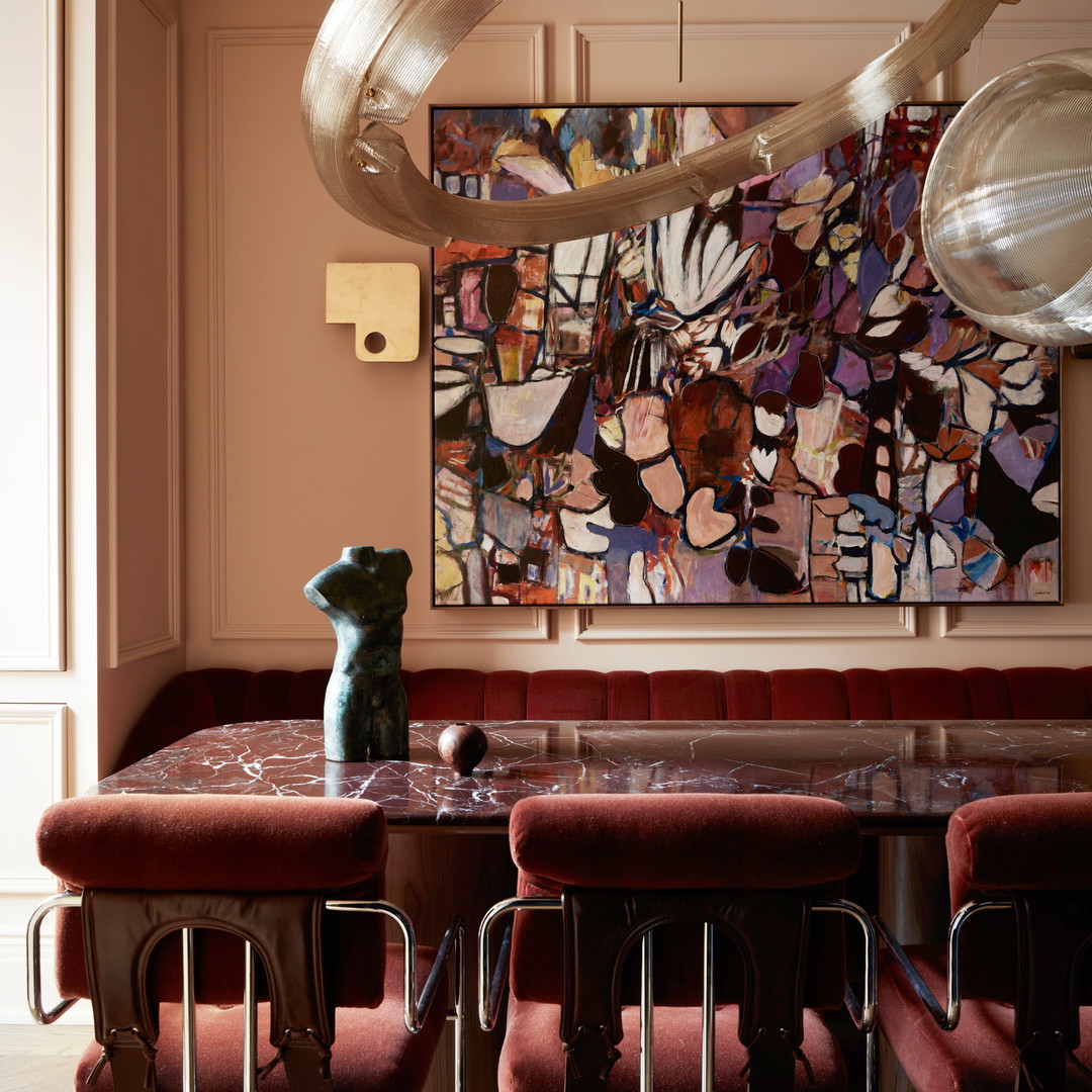 a dining room with a large painting hanging above the table