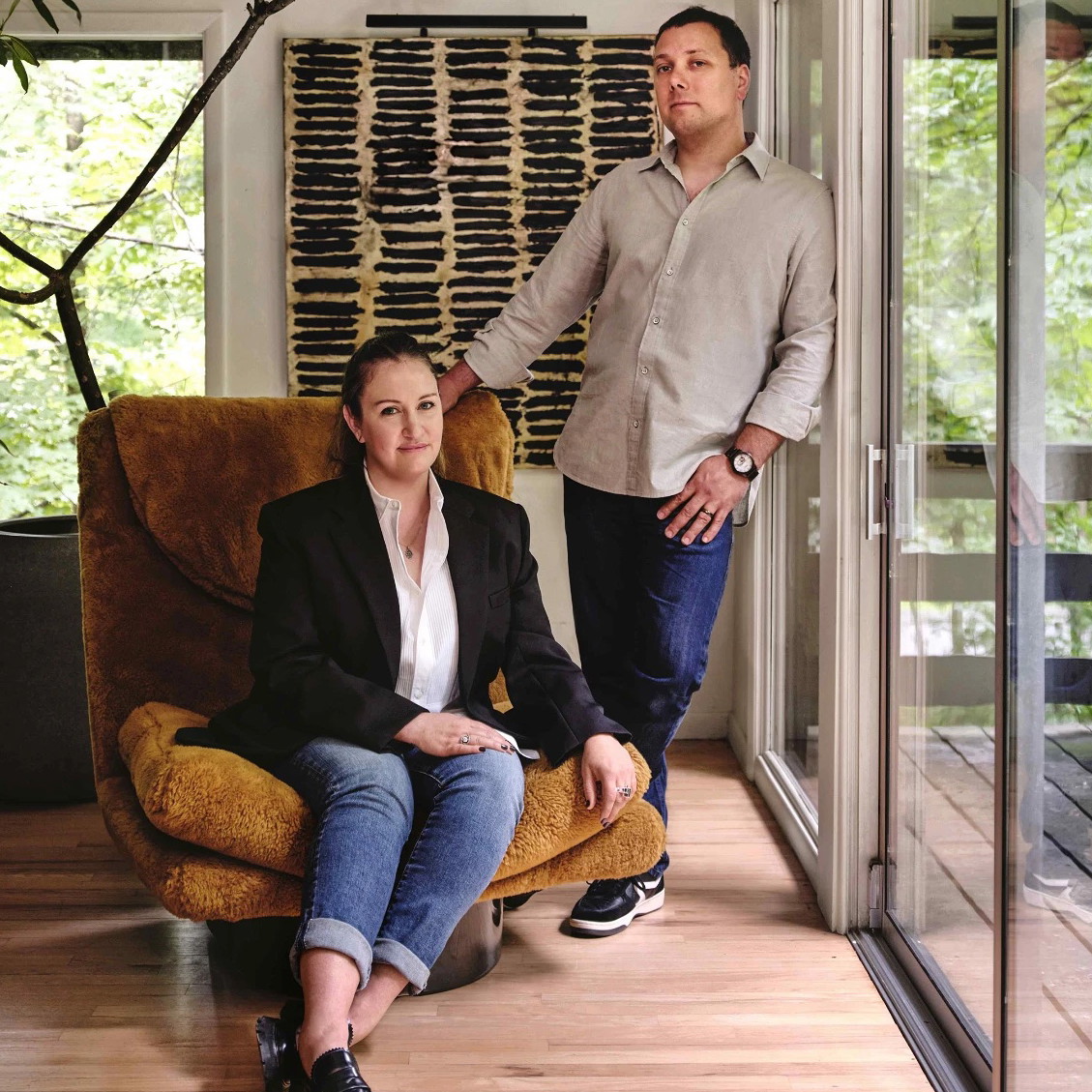 a man standing next to a woman sitting on a chair