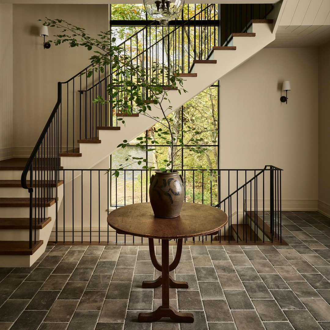 a table with a vase on top of it in front of a stair case