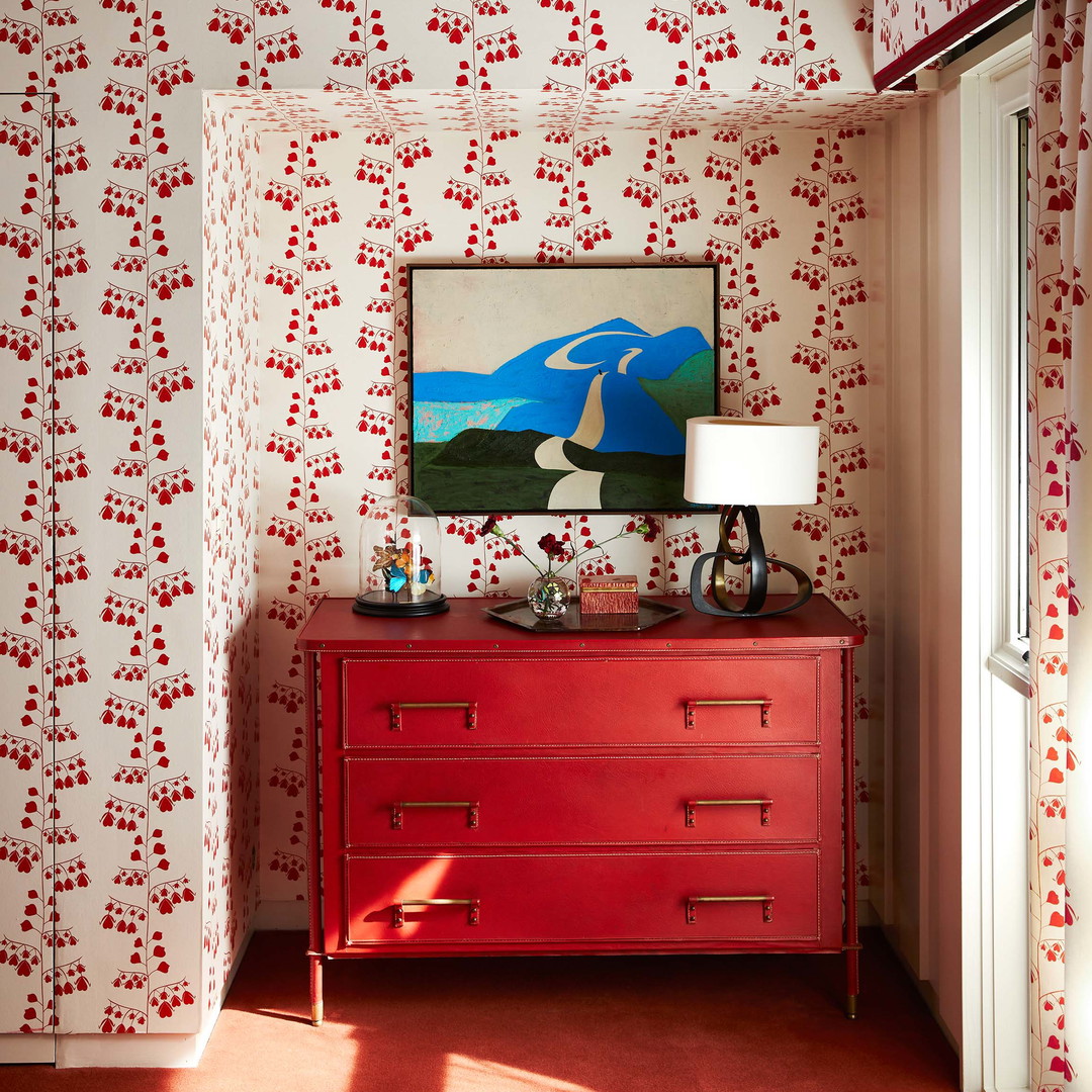 a red dresser with a painting on top of it
