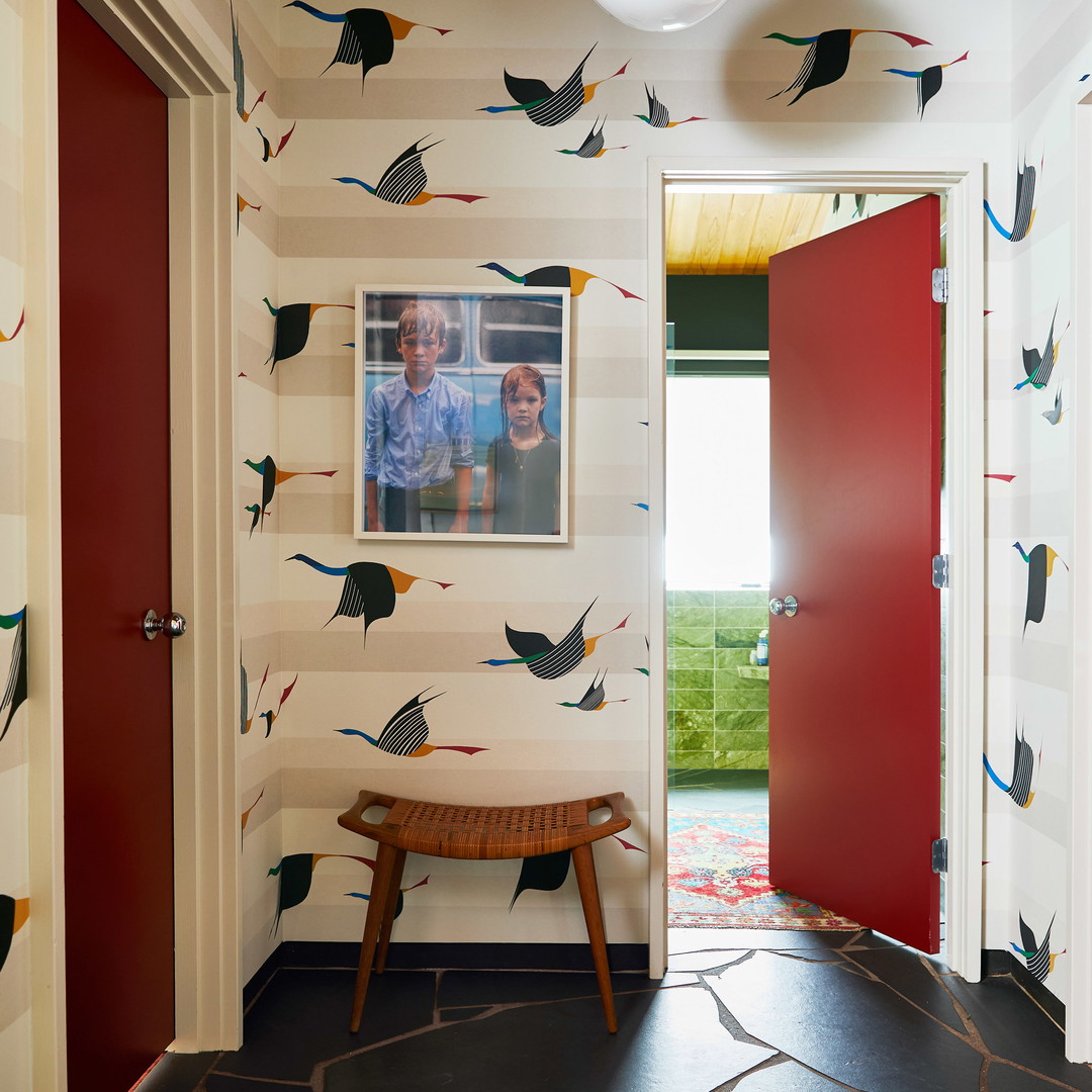 a hallway with a red door and a painting on the wall