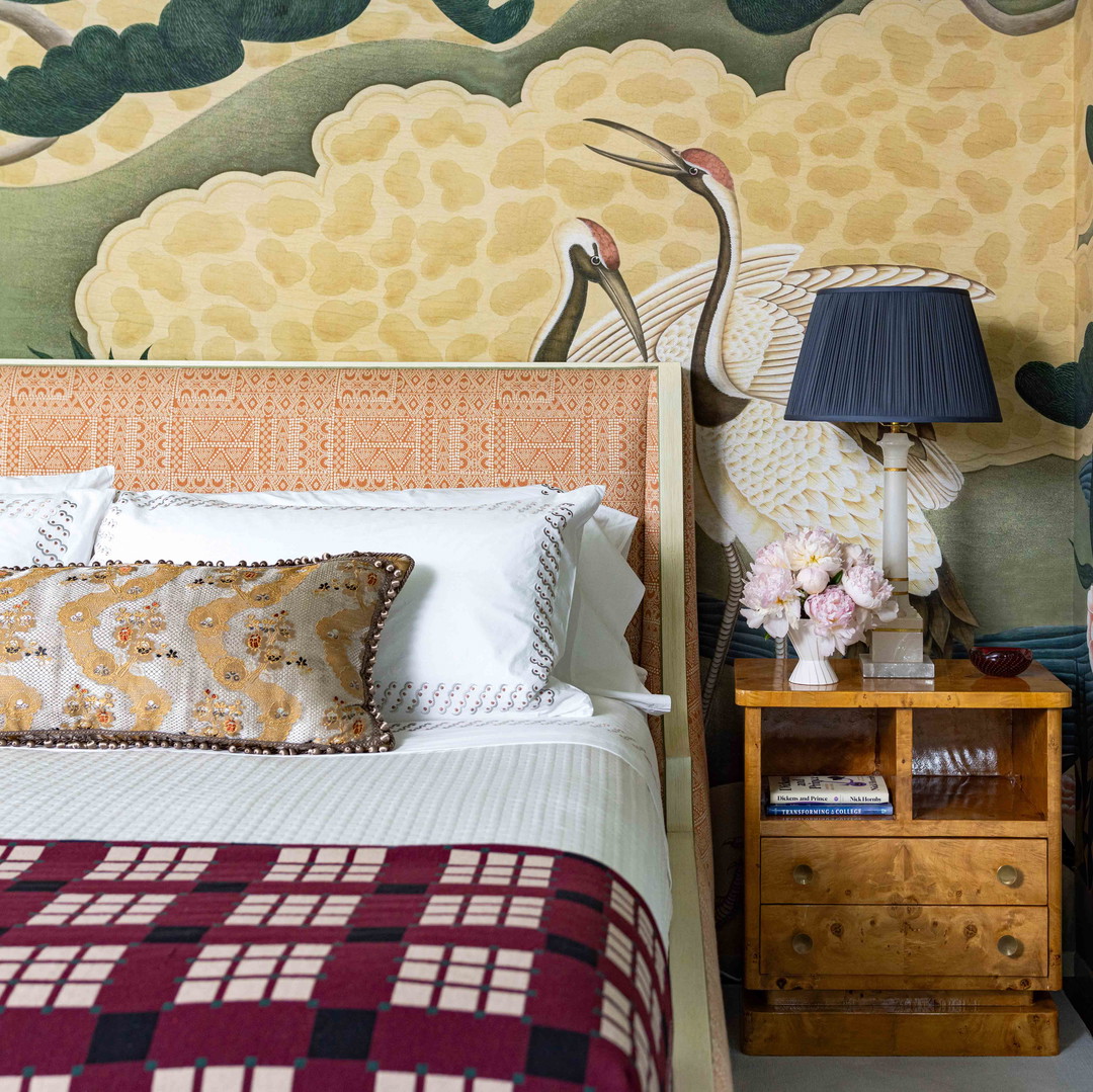 a bed sitting next to a nightstand with a lamp on top of it