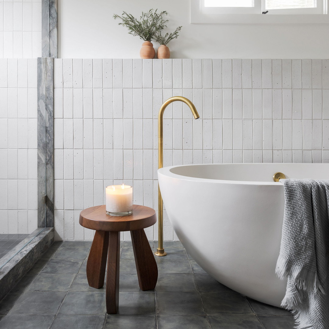 a white bath tub sitting next to a wooden stool