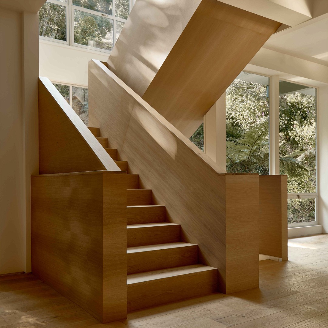 a wooden staircase in a house with large windows