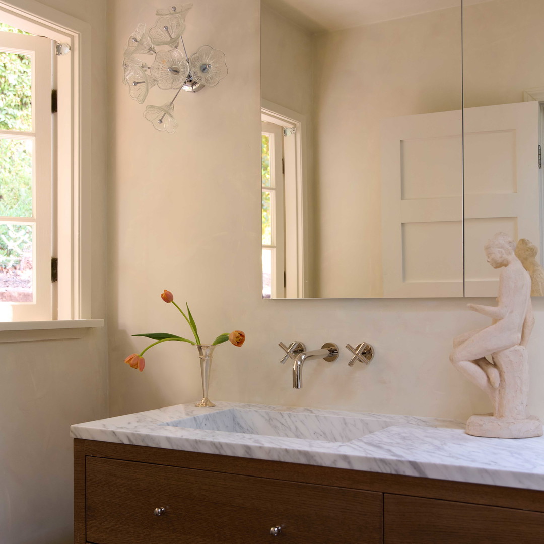 a bathroom with a sink, mirror and a vase with flowers